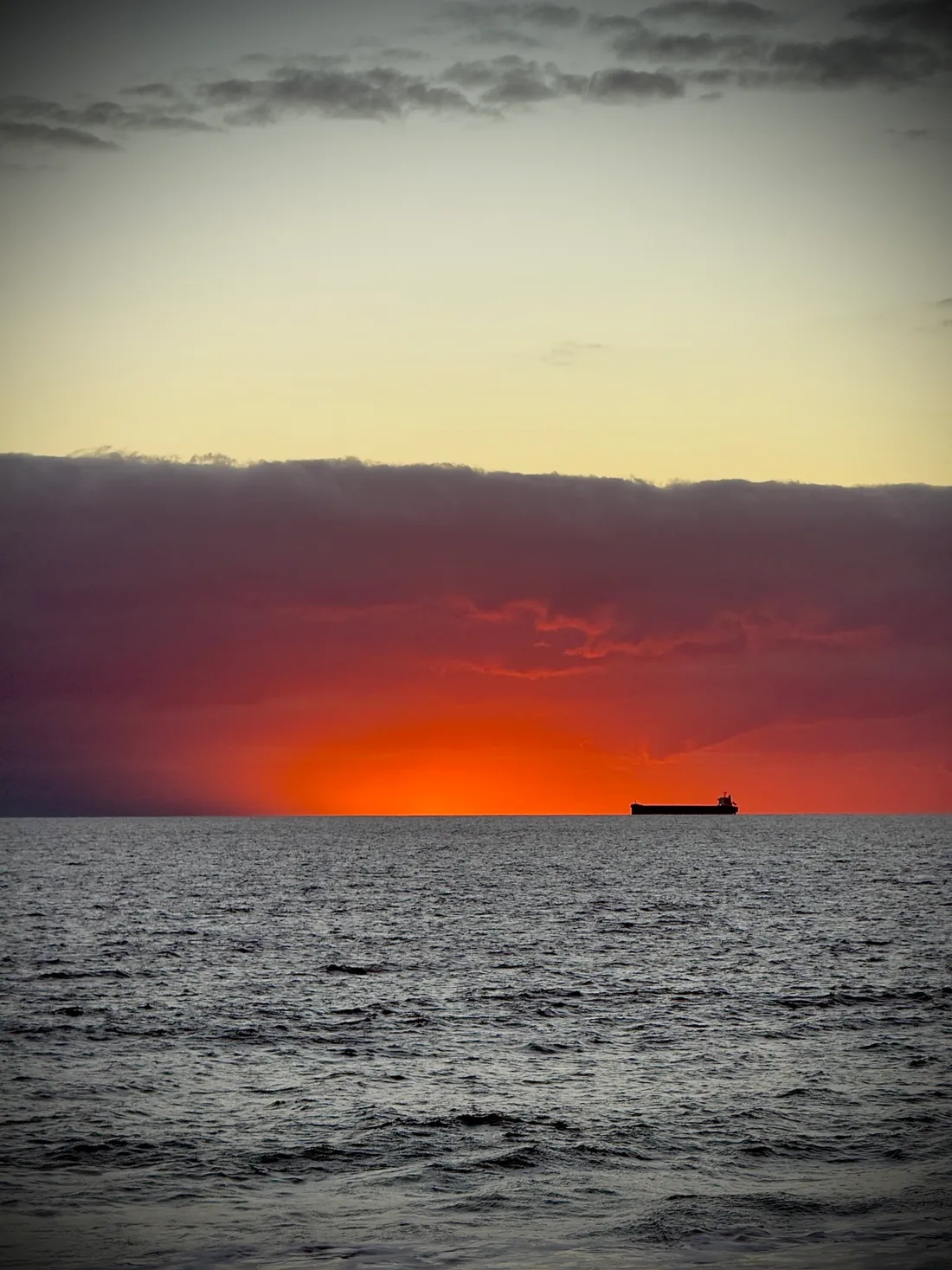 A ship on the horizon under a red sunset
